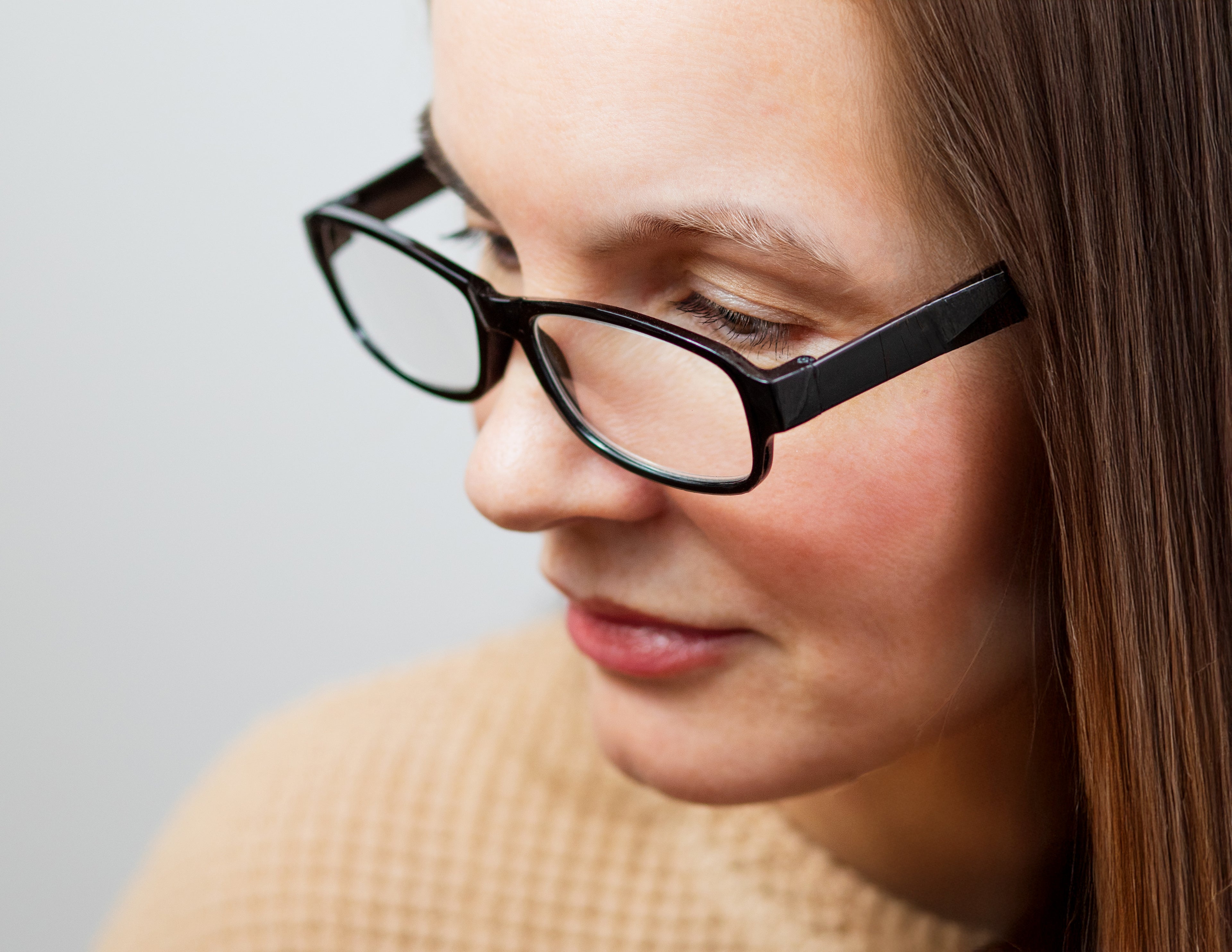 Close-up of a person wearing black eyeglasses against a light gray background