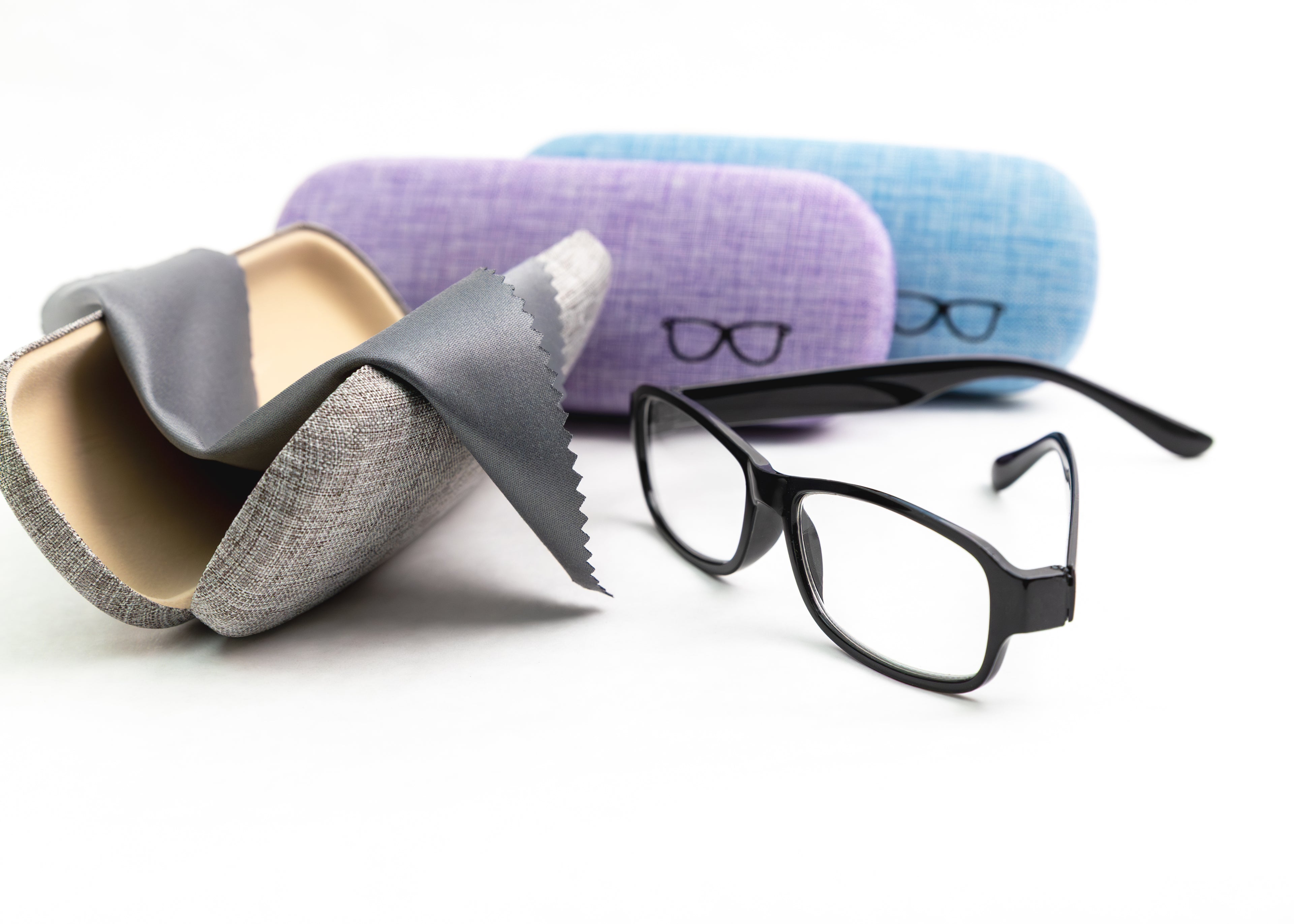 Eyeglasses with three different colored cases on a white background